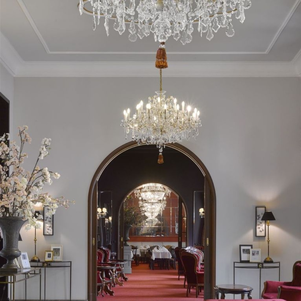 This European court-style multi-layer crystal chandelier features a gold metal frame paired with dense faceted crystals and candle-shaped lamp heads, with light refracting a brilliant halo through the crystals, serving both lighting and decorative purposes, suitable for luxury spaces such as high-end restaurants and hotel lobbies.