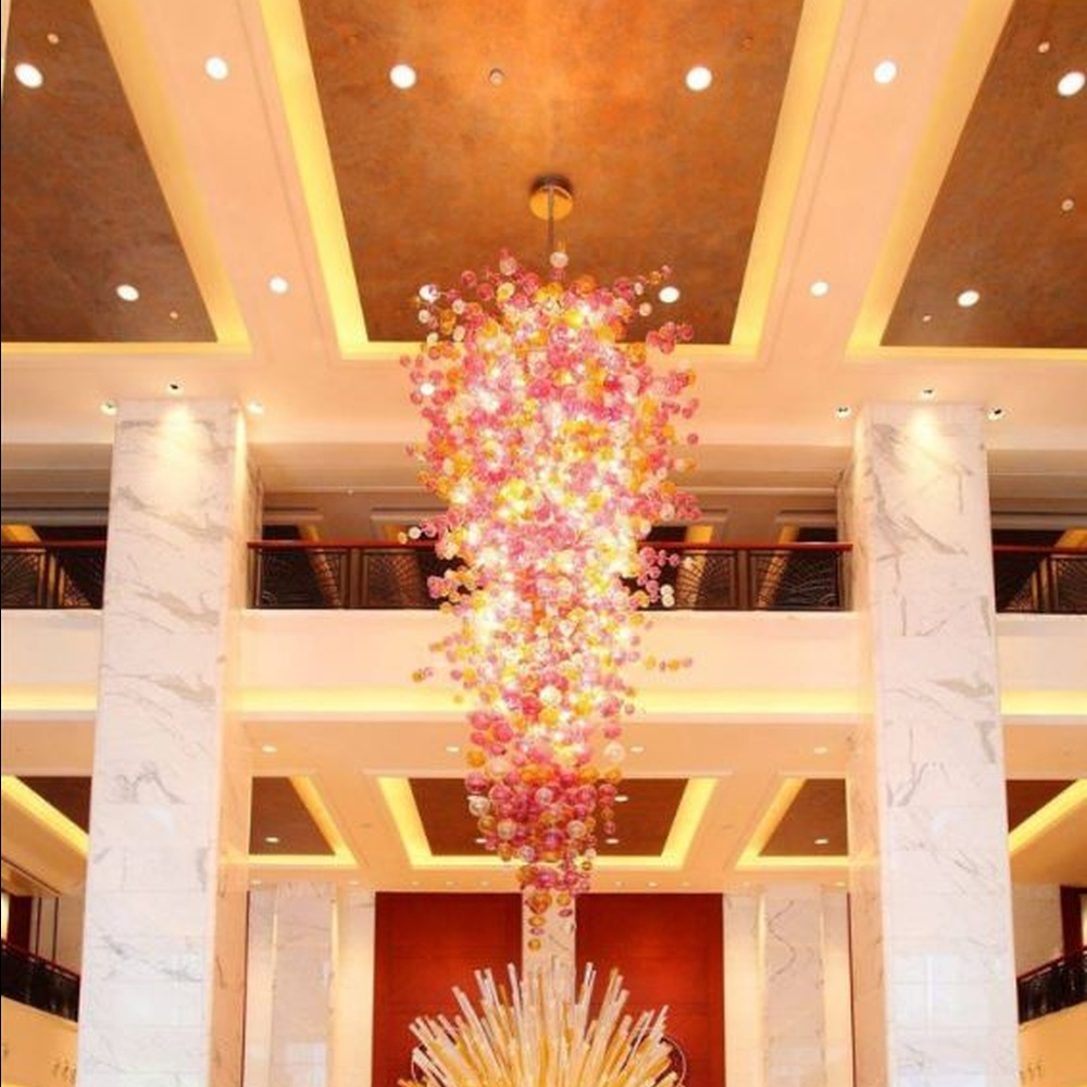Modern artistic flower cluster-shaped hanging chandelier, with pink-orange gradient crystal/acrylic petals stacked into a full flower cluster shape, combining artistic decoration and main lighting functions, suitable for high-ceiling large-scale spaces such as hotel lobbies, high-end clubs, and commercial atriums.
