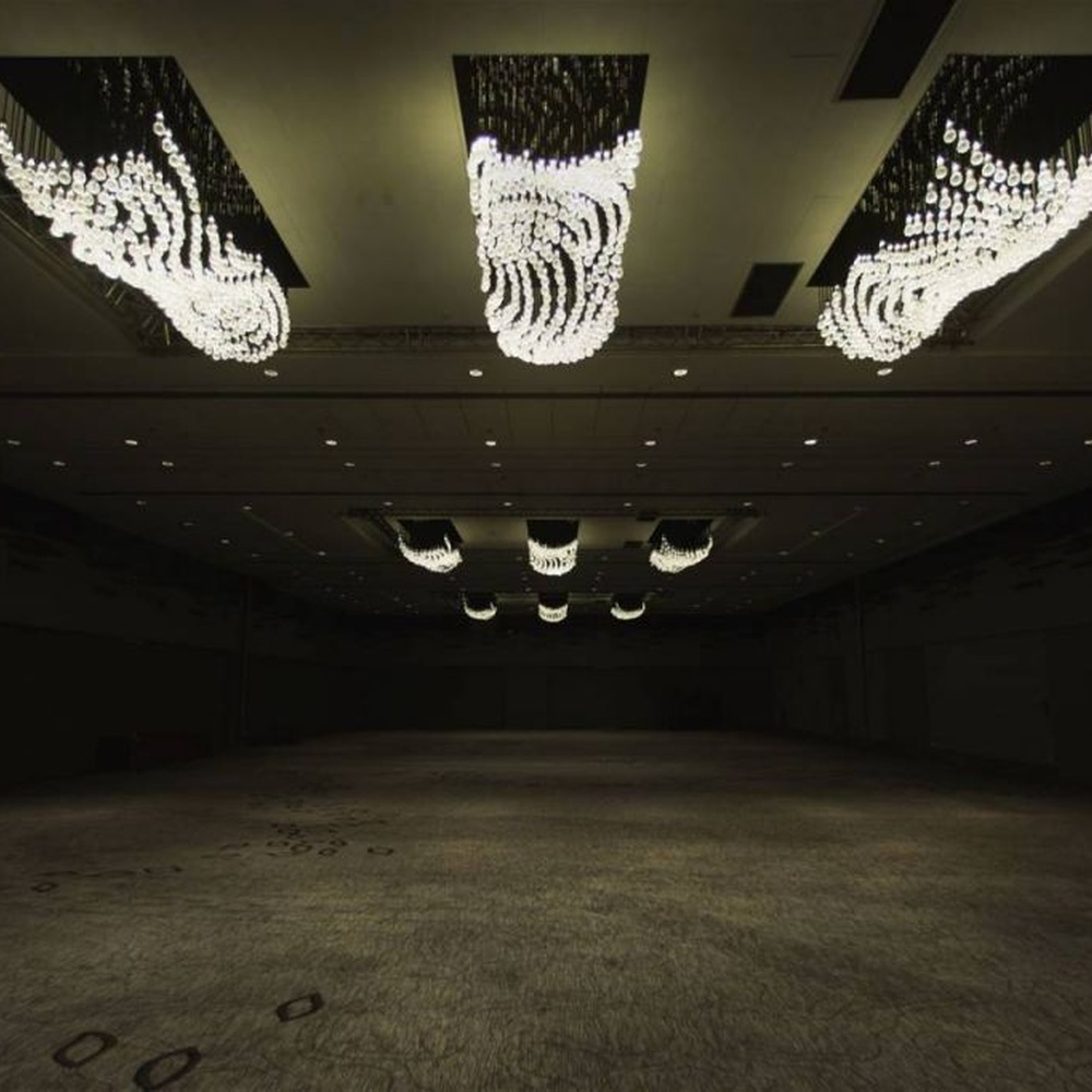 Modern artistic wavy hanging crystal chandelier, with a black metal frame and dense crystal particles creating a flowing wavy shape, combining decorative and main lighting functions, suitable for large-scale commercial spaces such as large banquet halls, exhibition centers, and high-end clubs.