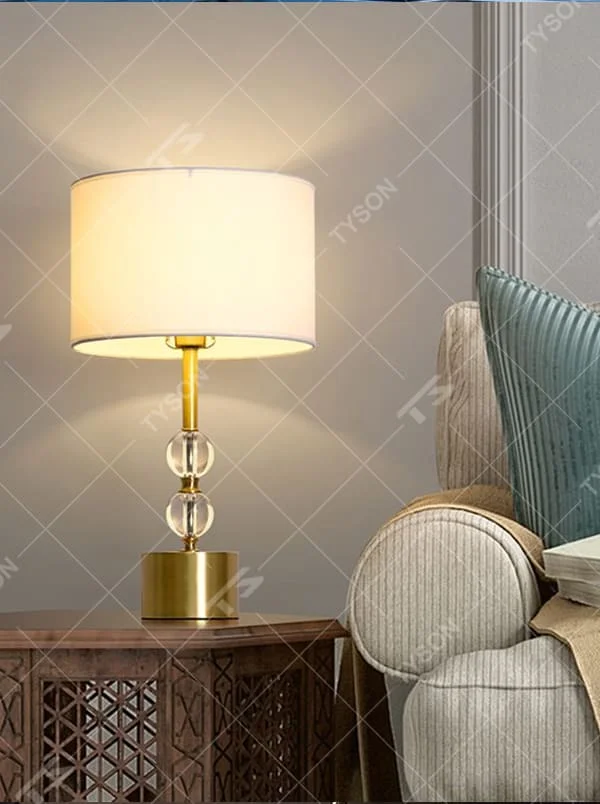 This is a luxury-style table lamp with a golden base, transparent glass spherical body, and beige fabric lampshade. It features a simple and elegant design with excellent texture. It is used for local desktop lighting and decoration, creating a luxurious and warm ambiance. It is suitable for luxury-style home bedroom bedside tables, high-end hotel guest rooms, modern apartment living spaces and other places.