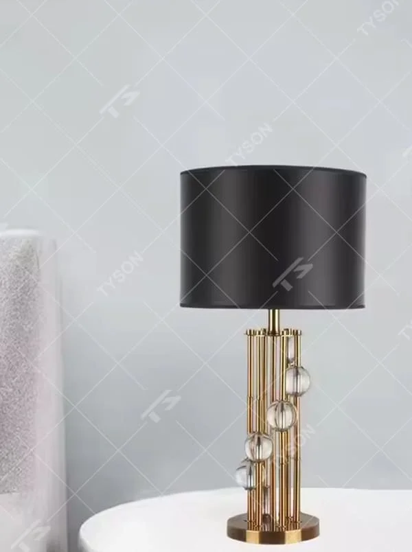 This is a luxury black-gold crystal table lamp, with a golden metal column (with multiple thin columns design) and transparent crystal balls, a black cylindrical fabric lampshade, featuring a modern luxury design with high-quality texture. It is used for local desktop lighting and decoration, creating a high-end luxury atmosphere. It is suitable for luxury-style home bedroom bedside tables, high-end hotel guest rooms, modern soft decoration display spaces and other places.