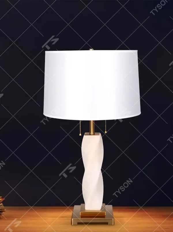 This is a modern artistic twisted table lamp, with a white twisted base, golden metal components, and a white fabric circular lampshade, featuring a strong artistic sense and luxury texture. It is used for local desktop lighting and decoration, creating an artistic luxury atmosphere. It is suitable for modern art home bedroom bedside tables, designer studios, high-end hotel guest rooms and other places.