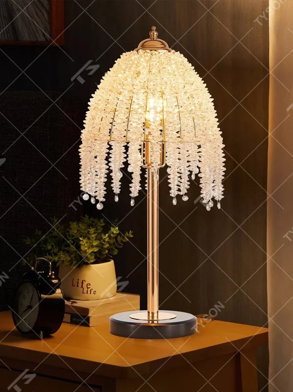 This is a luxury shell crystal table lamp with multi-layer shell-shaped crystal pendants, a golden bracket, and a black marble base, featuring a brilliant and luxurious design. It is used for local desktop lighting and decoration, creating a high-end luxurious atmosphere. It is suitable for luxury-style home bedroom bedside tables, high-end hotel guest rooms, European-style soft decoration spaces and other places.