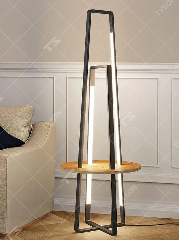 This is a modern geometric double-frame floor lamp with a black metal geometric frame, a wooden storage table, and built-in LED light strips, featuring a minimalist modern and functional design. It is used for space lighting, storage, and decoration, creating a modern luxury atmosphere. It is suitable for modern home living rooms, creative studios, luxury-style residences and other places.