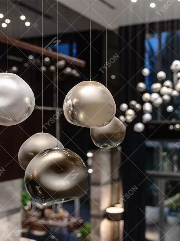 This is an artistic installation-style metal-textured glass sphere chandelier, with multiple irregular glass sphere lamps hanging in a scattered manner, featuring strong artistic sense, and the light reflects a unique visual effect. It is used for space lighting and artistic decoration, creating an artistic and modern atmosphere. Suitable for high-end hotel lobbies, art exhibition halls, modern art home living rooms and other places.