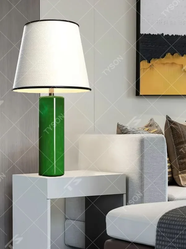 This is a modern fresh-style green cylindrical table lamp, with a green cylindrical base and a white fabric lampshade (black edging), featuring a minimalist modern design and fresh style. It is used for local desktop lighting and decoration, creating a fresh and modern atmosphere. Suitable for modern minimalist bedroom bedside tables, Nordic-style living room side tables, creative studios and other places.