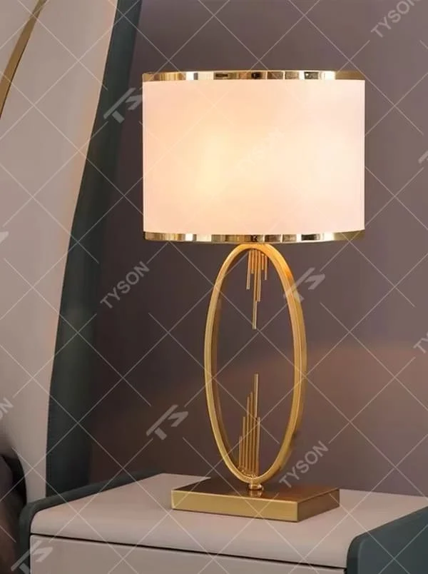 This is a light luxury artistic golden oval metal table lamp, with a golden metal oval frame with line decorations, paired with a beige fabric round lampshade. It features a light luxury and elegant design, with warm and soft lighting. It is used for local desktop lighting and decoration, creating a light luxury artistic atmosphere. Suitable for light luxury-style bedroom bedside tables, modern minimalist living room side tables, high-end hotel guest rooms and other places.