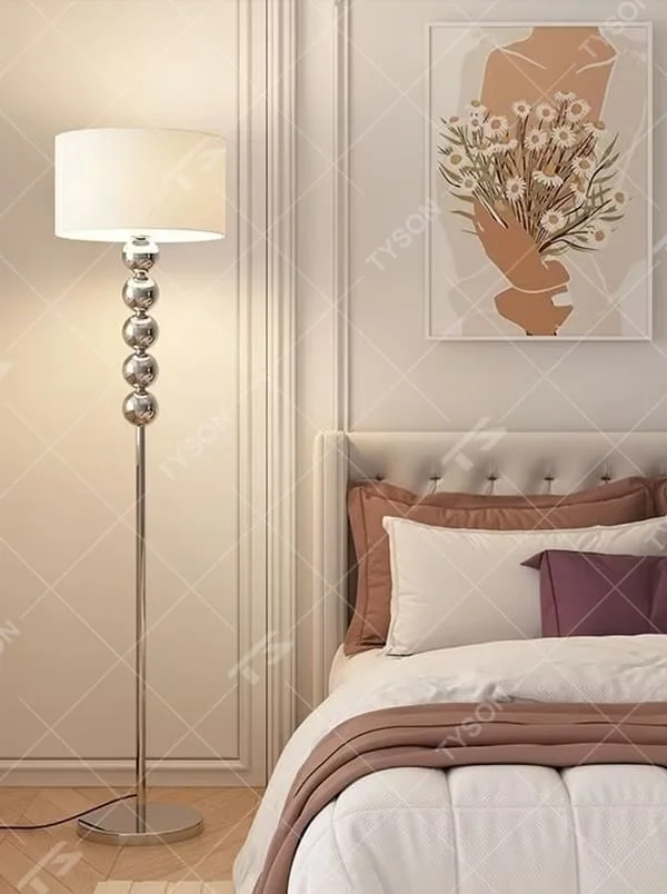 This is a modern warm-style black spherical decorative floor lamp, with a black metal pole featuring spherical decorative elements and a brown fabric lampshade. It has a minimalist and textured design, with soft lighting. It is used for space lighting and decoration, creating a warm and comfortable atmosphere. Suitable for modern minimalist bedrooms, living room corners, Nordic-style homes and other places.