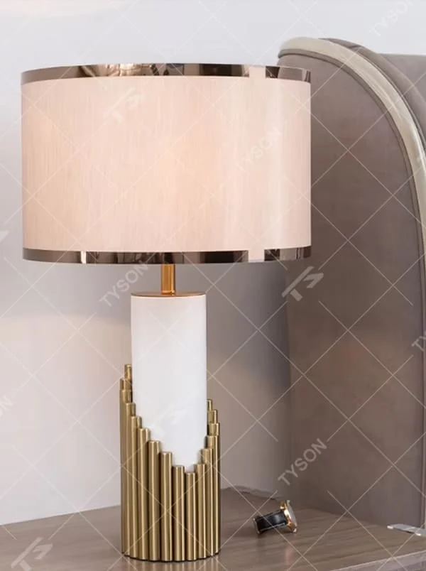 This is a light luxury-style gold and white metal fabric table lamp, with a golden staggered metal column base, paired with a white cylinder and a beige fabric lampshade (golden edging). It features a minimalist light luxury design, with warm and soft lighting. It is used for local desktop lighting and decoration, creating a light luxury and warm atmosphere. Suitable for light luxury-style bedroom bedside tables, modern minimalist living room side tables, high-end hotel guest rooms and other places.
