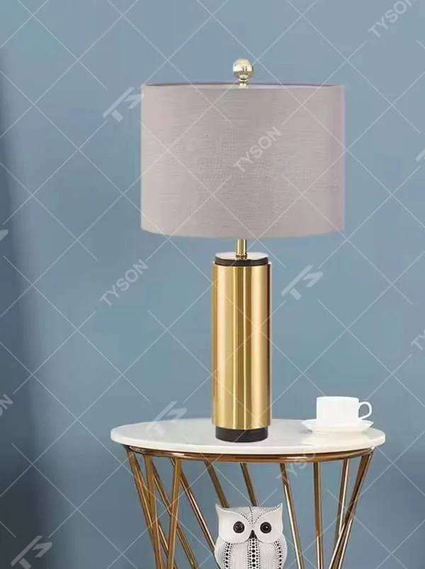 This is a luxury-style gold and gray table lamp, with a golden cylindrical base and a gray fabric circular lampshade, featuring a minimalist and grand design with strong luxury texture. It is used for local desktop lighting and decoration, creating a luxury and modern atmosphere. It is suitable for luxury-style home bedroom bedside tables, high-end hotel guest rooms, modern minimalist living room side tables and other places.