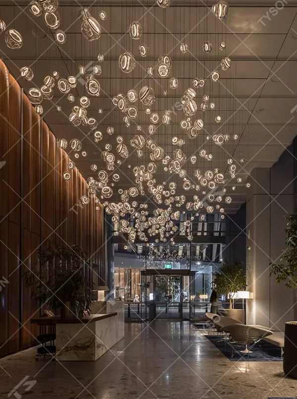 This is an artistic installation-style transparent glass ball chandelier, with numerous transparent glass balls of different sizes and shapes hanging in a scattered manner by thin wires. It features soft lighting and a strong sense of modern art and visual hierarchy. It is used for space lighting and artistic decoration, creating a modern artistic and ethereal atmosphere. Suitable for high-end hotel lobbies, art exhibition halls, atriums of large commercial centers and other places.