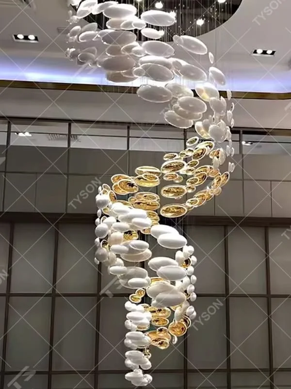 This is an artistic installation-style gold and white spiral glass piece chandelier, with numerous golden and white oval glass pieces hanging in a spiral and scattered manner, featuring strong artistic sense and visual impact, with brilliant light refraction. It is used for space lighting and artistic decoration, creating a luxurious artistic atmosphere. Suitable for high-end hotel lobbies, art exhibition halls, luxury shopping mall atriums and other places.
