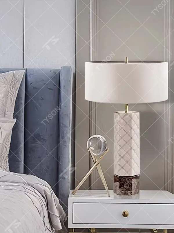 This is a light luxury elegant-style geometric textured column table lamp, with a beige fabric round lampshade, paired with golden metal connectors and a geometric textured column (marble texture at the bottom). It features an exquisite light luxury design, with warm and soft lighting. It is used for local desktop lighting and decoration, creating a light luxury elegant atmosphere. Suitable for light luxury-style bedroom bedside tables, modern minimalist living room side tables, high-end hotel guest rooms and other places.