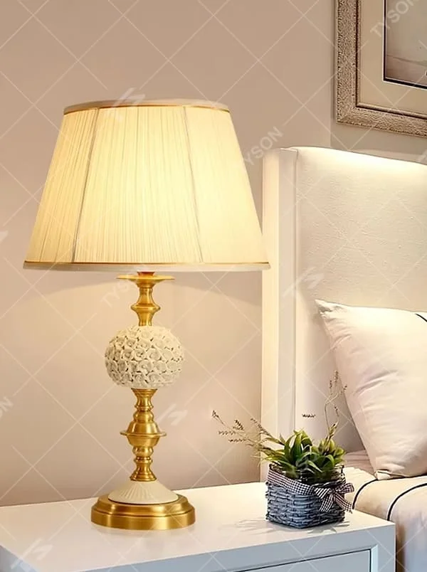 This is a European light luxury pleated fabric table lamp, with golden metal paired with a white carved spherical base, a beige pleated lampshade, soft and warm lighting, creating an elegant light luxury atmosphere.