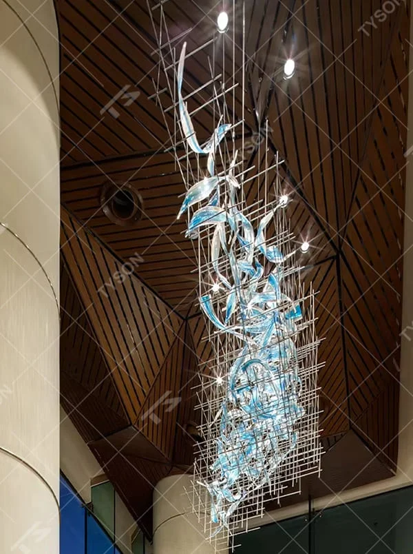 This is a modern artistic metal grid blue transparent decorative chandelier, with a metal grid as the frame, paired with flowing blue transparent shape decorations, and lights dotted in it, creating a dynamic artistic space atmosphere.