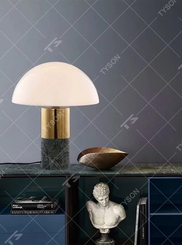 This is a light luxury minimalist hemisphere lampshade table lamp, with a white hemisphere lampshade paired with a golden metal + dark green marble base. It has an exquisite and high-end style, soft and warm lighting, creating a light luxury atmosphere.