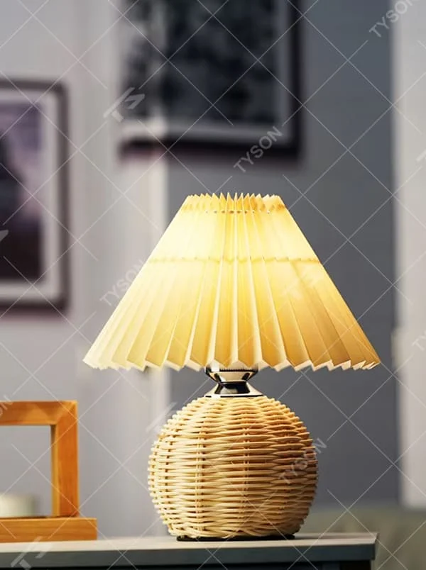 Natural minimalist rattan spherical table lamp, yellow pleated fabric lampshade paired with silver metal decorations, soft and warm lighting, creating a natural and comfortable space atmosphere.