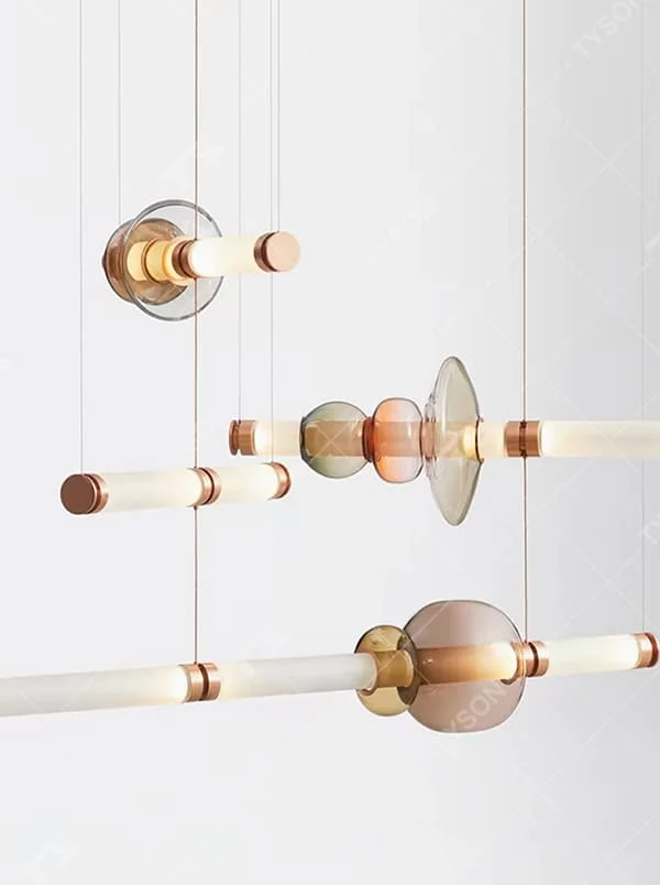 Modern artistic hanging combination chandelier, gradient glass components + copper metal decorations + milky white long tubes, soft lighting, creating an artistic minimalist atmosphere.