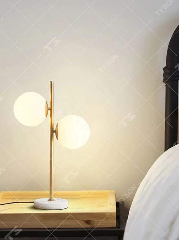 This is a modern light luxury double-ball table lamp, with a golden lamp pole paired with frosted white ball lampshades and a white marble base. The style is simple and exquisite, with soft and warm lighting.