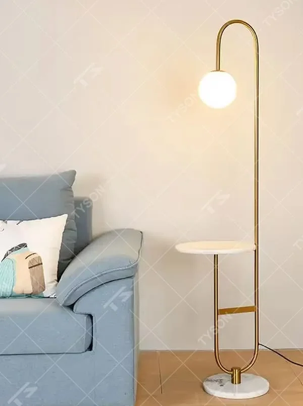 Modern light luxury golden curved floor lamp with table, white spherical lampshade + marble-patterned base, soft lighting, integrating lighting and storage functions, creating a minimalist high-end atmosphere.