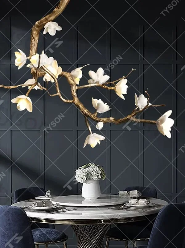 This is an artistic luxurious magnolia branch-shaped chandelier, with a golden simulated branch frame paired with white magnolia-shaped lampshades. The design combines natural artistic sense and luxurious texture, with soft and elegant lighting. It is used for space lighting and artistic decoration to create an artistic luxurious atmosphere. Suitable for light luxury-style dining rooms, luxury villa living rooms, high-end hotel banquet halls and other places.