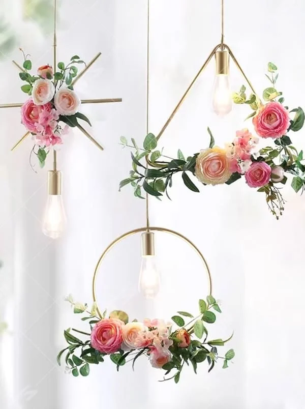 This is a romantic fresh-style geometric frame floral combination small chandelier, including golden metal star/triangle/circle frames, paired with pink-white artificial flowers and green plant decorations, and retro bulbs. The lighting is warm and soft, creating a romantic fresh atmosphere.
