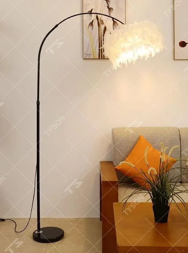 This is a warm romantic-style curved feather floor lamp, with a black curved lamp pole paired with a white feather lampshade and a black disc base. The lighting is soft and warm, creating a comfortable romantic space atmosphere.