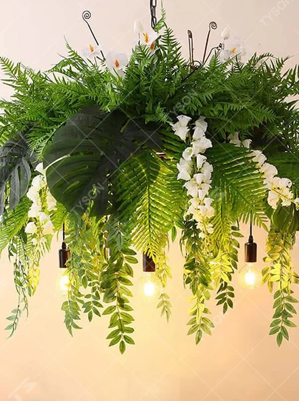 This is a natural and fresh-style artificial floral hanging chandelier, decorated with a large number of artificial green plants (ferns, monstera leaves) and white flowers, paired with retro bulbs and a hanging structure. The design is natural and warm, with soft warm yellow lighting. It is used for space lighting and decoration to create a natural retro atmosphere. Suitable for literary cafes, Nordic-style homestays, nature-themed restaurants and other places.