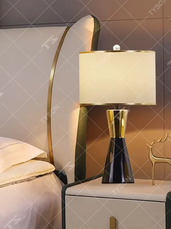 This is a light luxury black-gold cone table lamp, with a black cone base paired with golden decorations, a beige cylindrical lampshade with golden trim, soft and warm lighting, creating an elegant light luxury atmosphere.