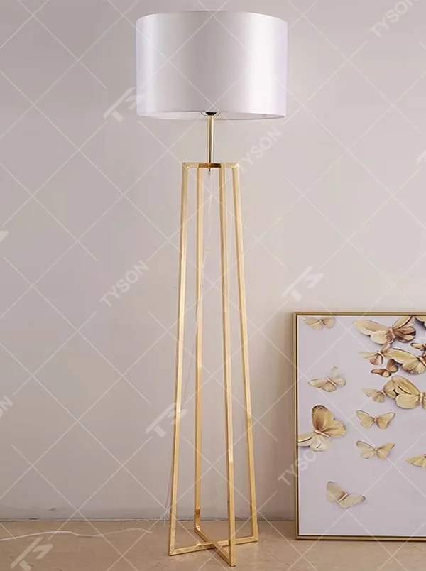This is a light luxury minimalist golden geometric frame floor lamp, featuring a golden triangular geometric frame lamp pole paired with a white cylindrical fabric lampshade. It has a minimalist and grand design, with soft and uniform lighting. It is used for space lighting and decoration, creating a light luxury minimalist atmosphere. Suitable for light luxury-style living rooms, modern minimalist bedrooms, high-end apartments and other places.