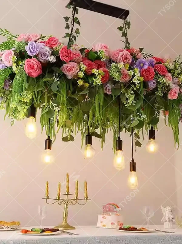 This is a romantic natural-style long strip floral chandelier, decorated with colorful artificial flowers (pink/purple/red roses) + green plants as the main body, paired with retro bulbs, featuring a fresh and romantic style, with warm and soft lighting.