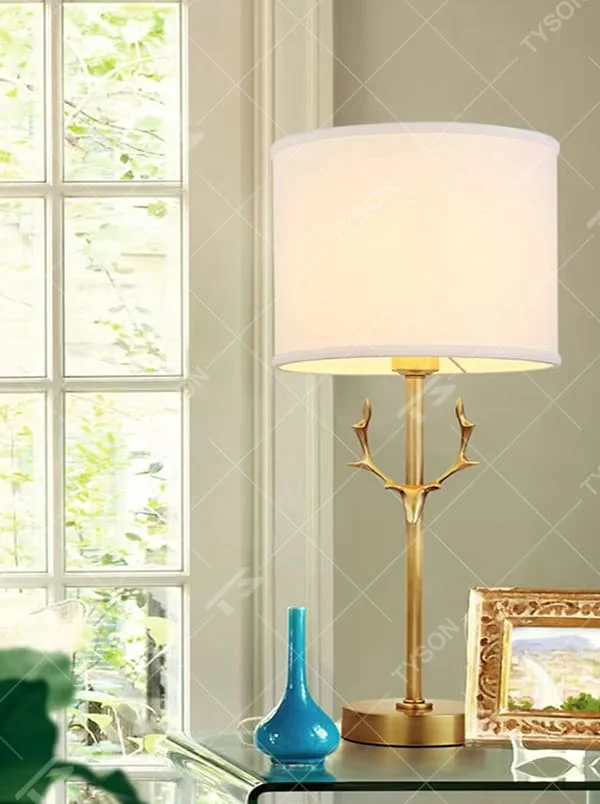 Light luxury golden antler-shaped table lamp, white cylindrical fabric lampshade + golden base, soft and warm lighting, creating a natural elegant atmosphere.