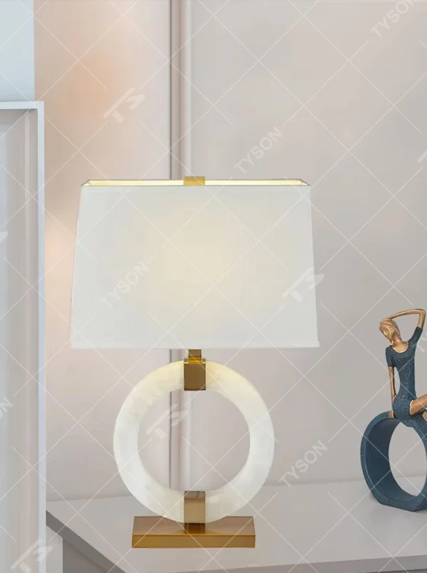 Light luxury white jade ring base table lamp, white jade-textured ring + golden metal decorations + white fabric lampshade, soft warm light, creating a light luxury elegant home atmosphere.