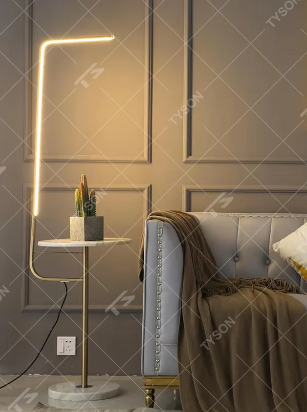 Light luxury golden L-shaped LED strip floor lamp with transparent side table, golden metal L-shaped stand + transparent round side table + white marble base, soft warm light, creating a high-end practical light luxury atmosphere.