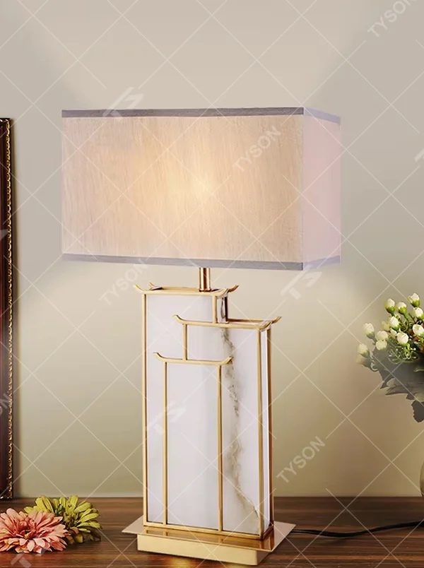 New Chinese light luxury gold frame ink texture table lamp, gold window lattice-like metal frame + ink texture panel + beige fabric lampshade, soft lighting, creating an elegant new Chinese atmosphere.