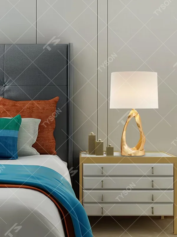 Art light luxury golden irregular twisted hollow base table lamp, beige fabric cylindrical lampshade, soft warm light, creating a high-end art light luxury atmosphere.