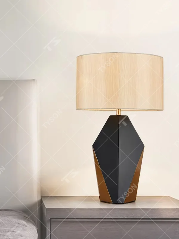 Light luxury black-gold geometric diamond base table lamp, black geometric diamond base + golden decorative details + beige fabric lampshade, soft warm light, creating a high-end light luxury bedroom atmosphere.