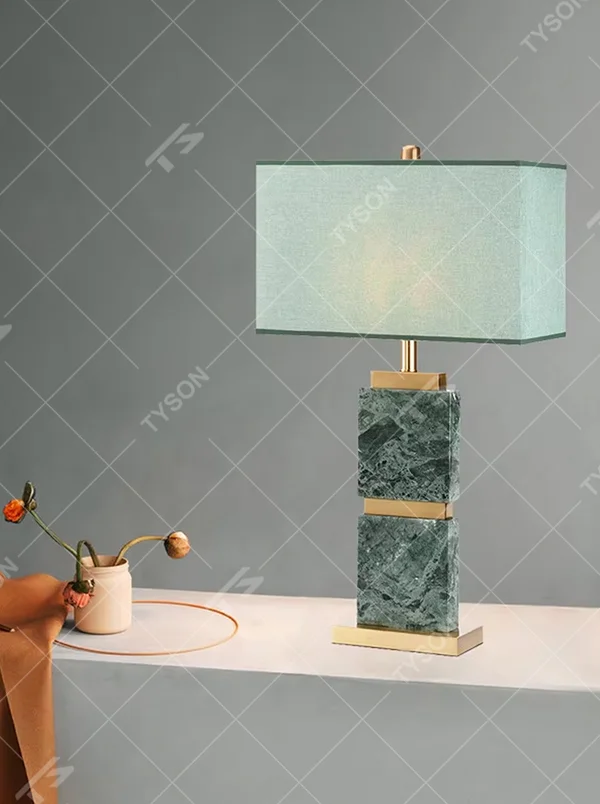 Light luxury dark green marble gold-decor light cyan fabric lampshade table lamp, square marble base + golden decorative strips + light cyan fabric lampshade, soft light, creating a high-end light luxury atmosphere.