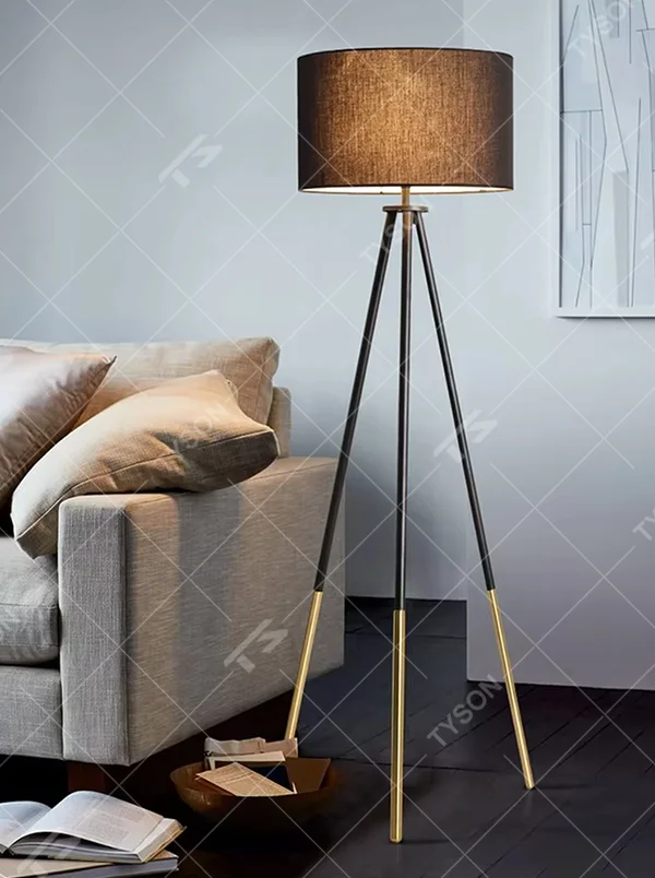 Light luxury black-gold spliced tripod floor lamp, brown fabric cylindrical lampshade + black pole gold foot stand, soft lighting, creating a high-end minimalist atmosphere.