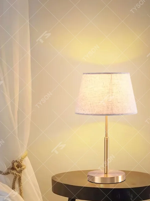 Modern light luxury golden metal pole linen texture fabric shade round base table lamp, warm light effect, creating an elegant minimalist home atmosphere.