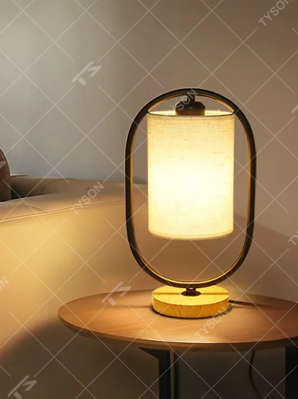 Modern minimalist silver oval metal frame linen texture lampshade wooden base table lamp, warm light effect, creating a cozy minimalist home atmosphere.