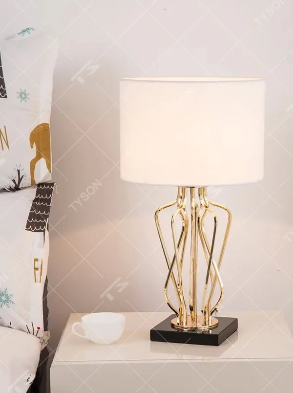 Modern luxurious black-gold geometric interwoven metal stand table lamp (black fabric lampshade + golden interwoven poles + black base), warm light effect, creating a high-end artistic atmosphere.