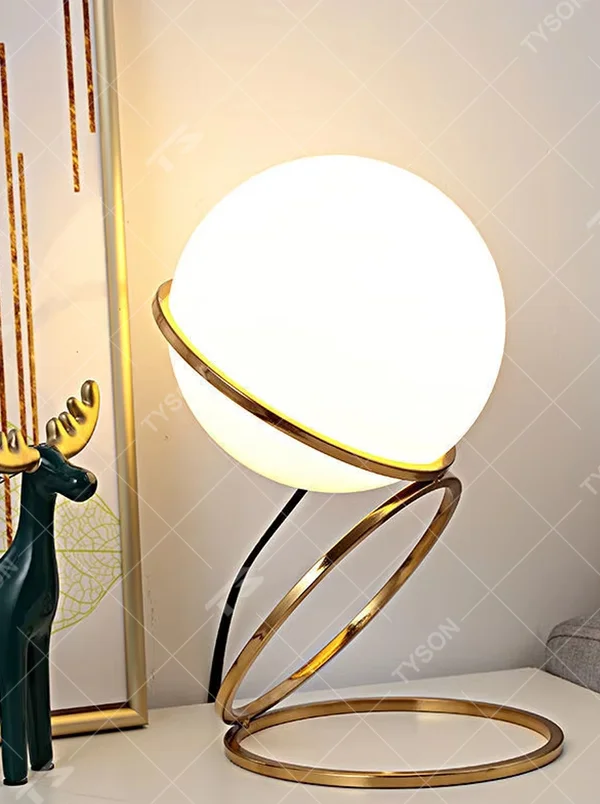 Modern planet orbit-shaped table lamp (white ball + gold ring stand), warm light effect, creating a sci-fi artistic minimalist space atmosphere.