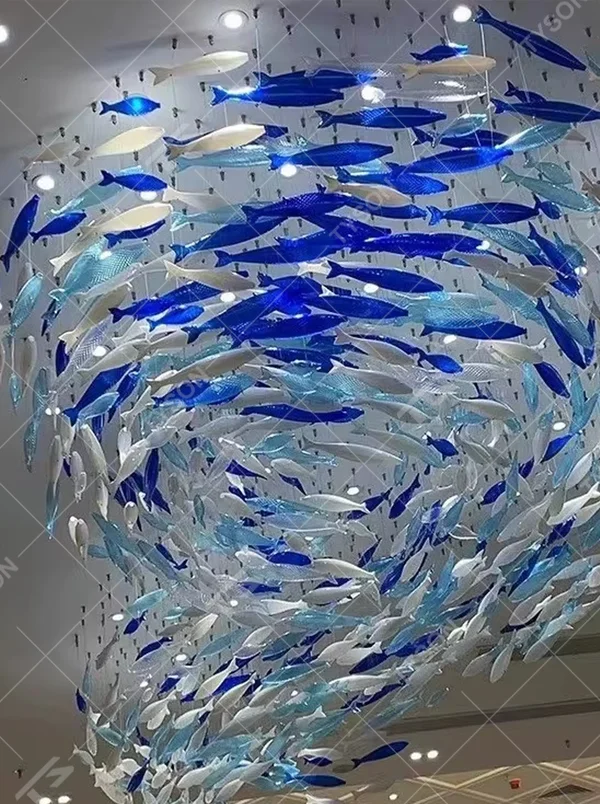 Art fish school-shaped chandelier (blue-white gradient glass fish + warm light), warm light effect, creating a dynamic and natural atmosphere for high-end public spaces.
