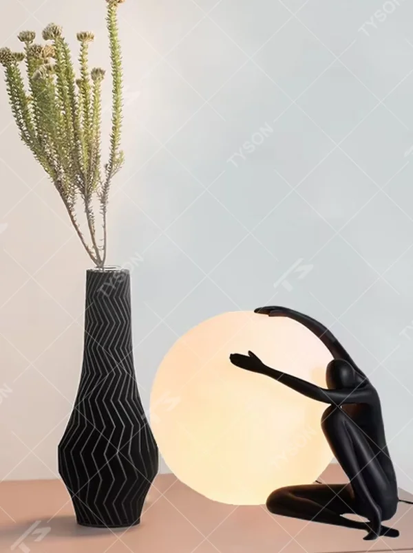 Artistic humanoid sculpture lifting spherical soft light table lamp (black sculpture + warm light ball shade), warm light effect, creating a creative artistic space atmosphere.