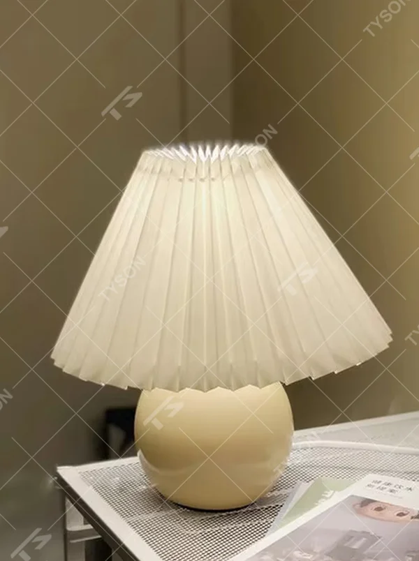 Fresh pleated umbrella shade table lamp (cream yellow glaze ball body + white pleated shade), warm light effect, creating a soft and healing home atmosphere.