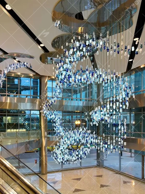 Art blue-white glass bead spiral chandelier (gradient color beads + curved shape), warm light effect, creating a dynamic artistic atmosphere for high-end public spaces.