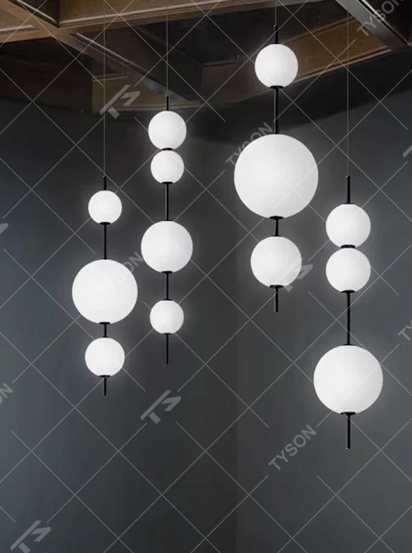 Modern tiered glass ball chandelier (black-white tiered balls + minimalist hanging rod), warm light effect, creating a simple and artistic space atmosphere.