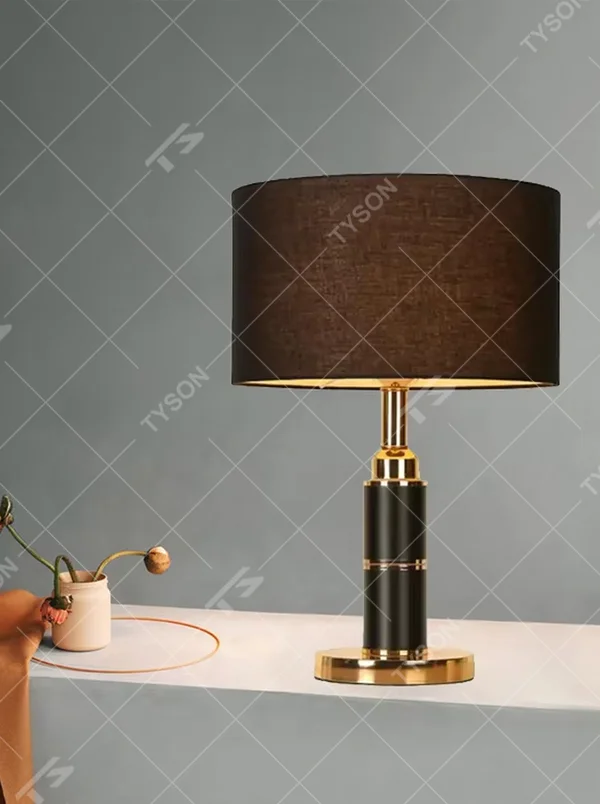 Light luxury brown fabric shade black-gold cylindrical base table lamp, warm light effect, creating a calm and high-end space atmosphere.