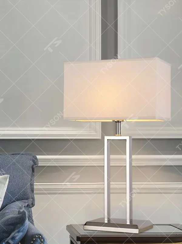 Modern minimalist geometric metal table lamp (bright chrome hollow lamp base + rectangular fabric lampshade), warm light effect, creating an exquisite and high-end home and office atmosphere.